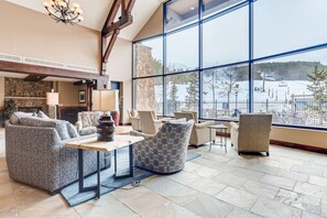 A spacious living area with a large window offering a view of a snowy landscape. Furnishings include a sofa, armchairs, and a coffee table. - Modern Breckenridge Penthouse.  Ski-in/ski-out! (Breckenridge)