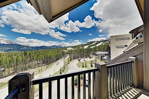 A balcony with a view of a road, trees, and mountains.