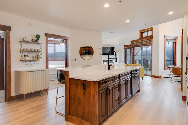 A spacious kitchen with a large island, wooden cabinets, and a view of the city.