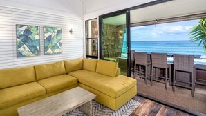 Un canapé jaune, une table basse en bois et un coin repas avec des chaises en osier.