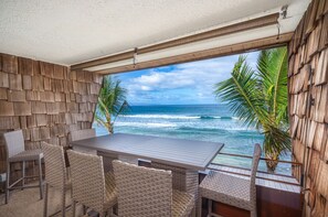 An outdoor seating area with a view of the ocean, wicker furniture, and a wooden wall. - Oceanfront beach renovation. Direct water views! (Lahaina)