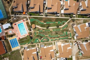 An aerial view of a residential area with houses, a swimming pool, and a golf course.