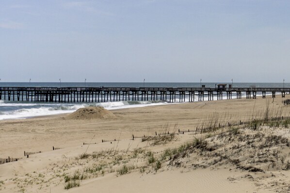 Enjoy a serene beach experience with a wooden pier stretching into the ocean, perfect for a relaxing stroll.