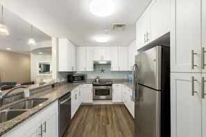 Enjoy cooking in this well-equipped kitchen with a refrigerator, oven, and microwave, featuring a double sink and pendant lighting.