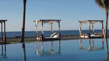 Un espace aménagé au bord de la piscine, avec des cabanas et une vue sur l’océan.