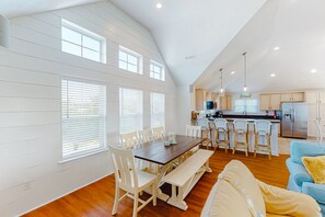 Enjoy meals at the central dining table surrounded by comfortable seating and a fully equipped kitchen.
