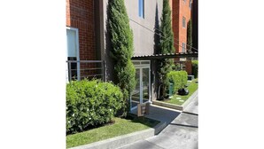 Un bâtiment moderne avec une entrée en verre, entouré d’un espace vert bien entretenu et bordé d’un trottoir dégagé.