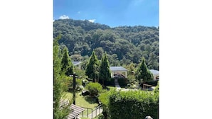 Un paysage verdoyant et luxuriant, avec un ciel dégagé, un sentier menant à un bâtiment et une forêt dense en arrière-plan.