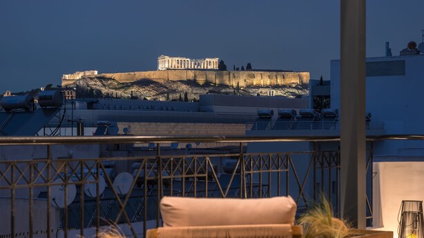 Une terrasse offrant une vue sur une forteresse ancienne, un coin repas avec une table et des chaises, et des panneaux solaires sur le toit.