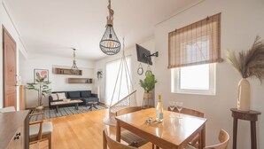 Un espace de vie moderne comprenant un coin repas, un canapé et un téléviseur fixé au mur.