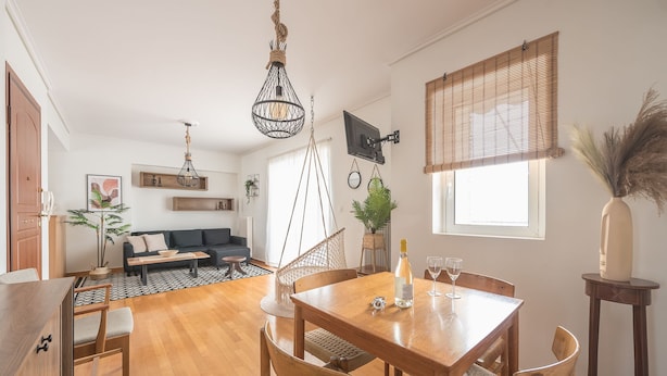 A modern living space with a dining area, a sofa, and a TV mounted on the wall.