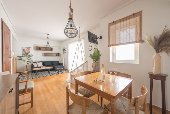 A modern living space with a dining area, a sofa, and a TV mounted on the wall. - Parthenon dream, breathtaking views with free parking  (Αθήνα)