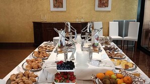 A buffet table with various food items and a fruit bowl. - Hotel Falcone (Lignano Sabbiadoro)