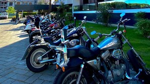 A row of parked motorcycles in front of a multi-story building with balconies. - Hotel Falcone (Lignano Sabbiadoro)