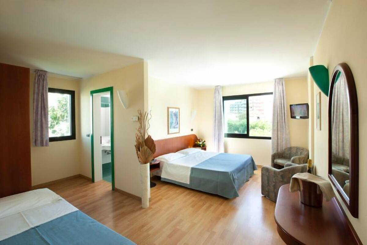 Une chambre d’hôtel avec un lit, une chaise, un bureau et une grande fenêtre.