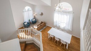 Un'ampia zona giorno con una scala bianca, un tavolo da pranzo con sedie e un divano.