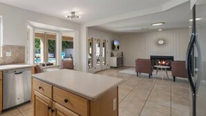 Una cucina moderna con isola centrale, lavastoviglie integrata e camino.