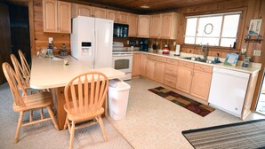 A kitchen with wooden cabinets, a refrigerator, stove, and a sink.