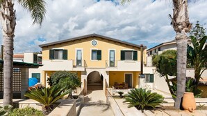A two-story building with a central entrance, surrounded by palm trees and a paved walkway. - For a dream vacation to the Ionian Sea 5 sails (San Lorenzo  Reitani)