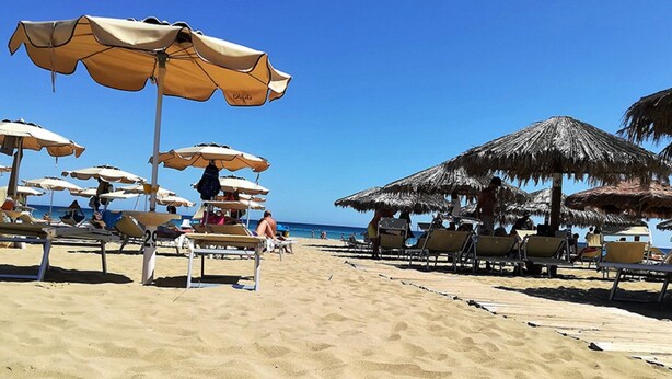 A beach with sun loungers and umbrellas, a clear blue sky, and the ocean in the background. - For a dream vacation to the Ionian Sea 5 sails (San Lorenzo  Reitani)