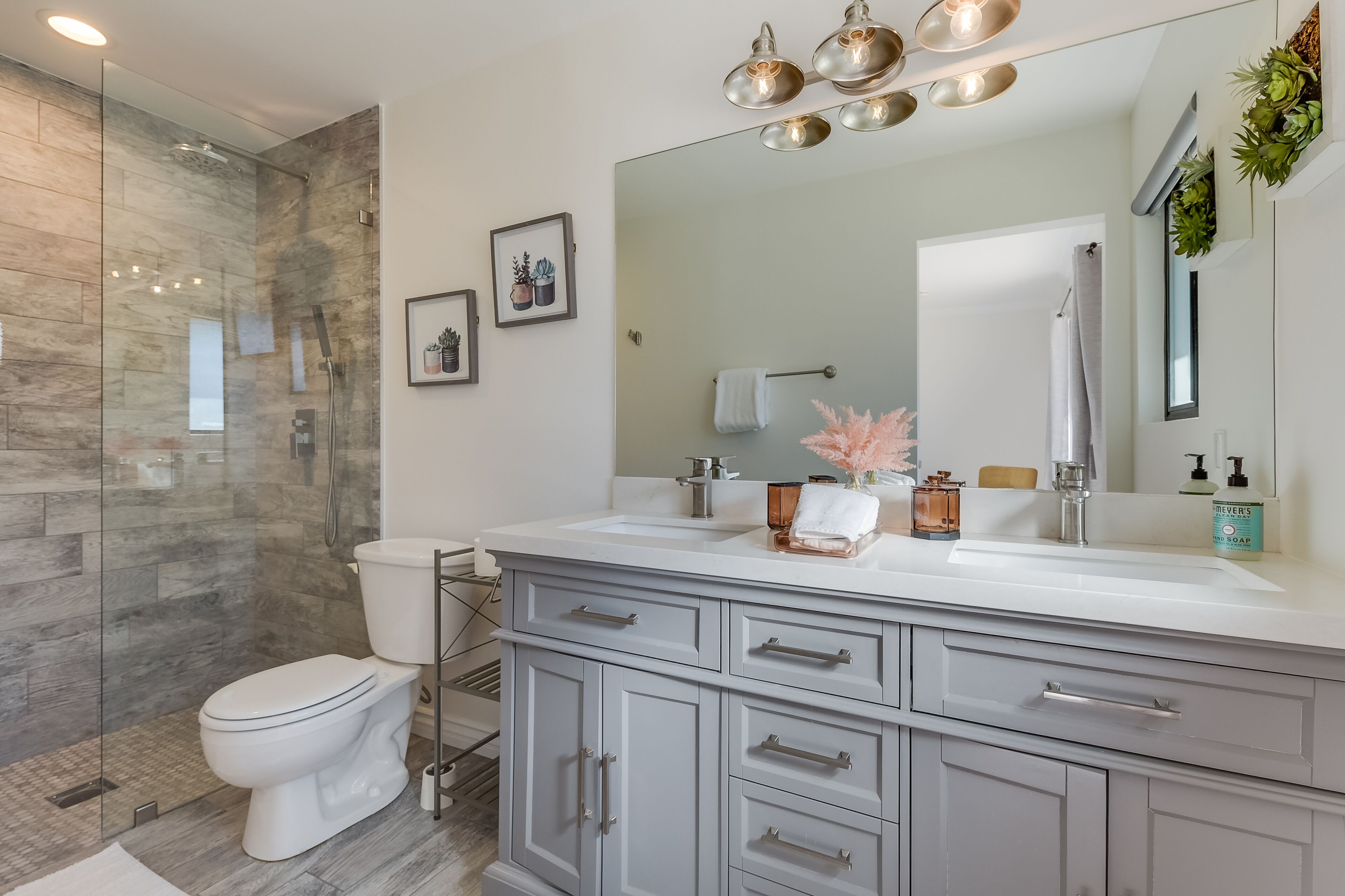 A modern bathroom with a glass shower enclosure, a white toilet, and a vanity with a large mirror.