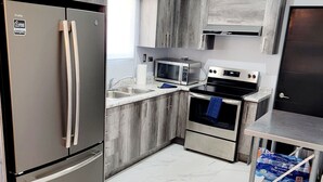 Eine moderne Küche mit Edelstahl-Kühlschrank, Mikrowelle, Backofen und Spüle.