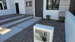Ein modernes Gebäude mit flachem Dach, einer Tür und einem Fenster. An der Wand befindet sich die Nummer 6.
