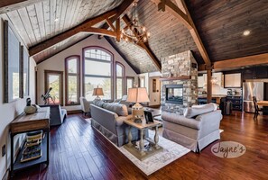 Un salón espacioso con techo alto, chimenea de piedra y ventanas amplias.