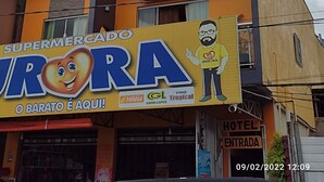 Un edificio de varios pisos con un letrero que dice 'Hotel Rio' y un letrero de 'Supermercado' debajo.