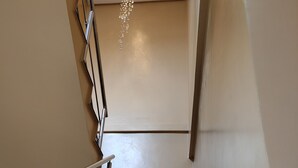 Una escalera con barandillas de metal, un candelabro y un interruptor de luz en la pared.