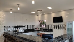 Una cocina moderna con una isla central, salpicadero con diseño blanco y negro, y un televisor de pantalla plana montado en la pared.