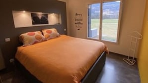 Un dormitorio moderno con una cama grande, una ventana con vistas y una lámpara fijada a la pared.