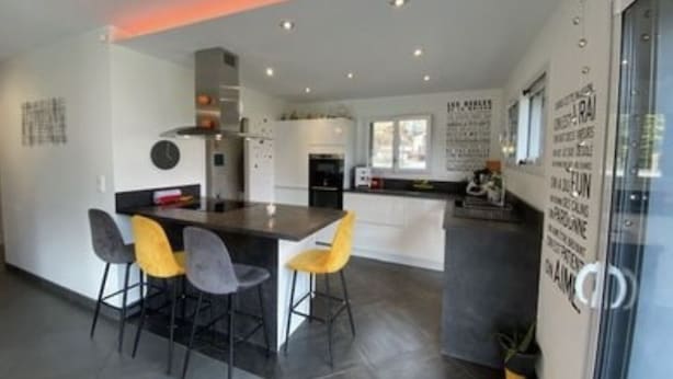 Una cocina moderna con una isla central, taburetes de bar y una mesa de comedor.