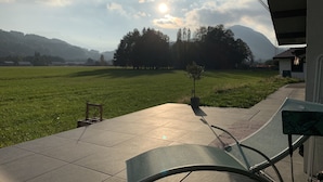 Un patio con vista a un campo verde y montañas a lo lejos.