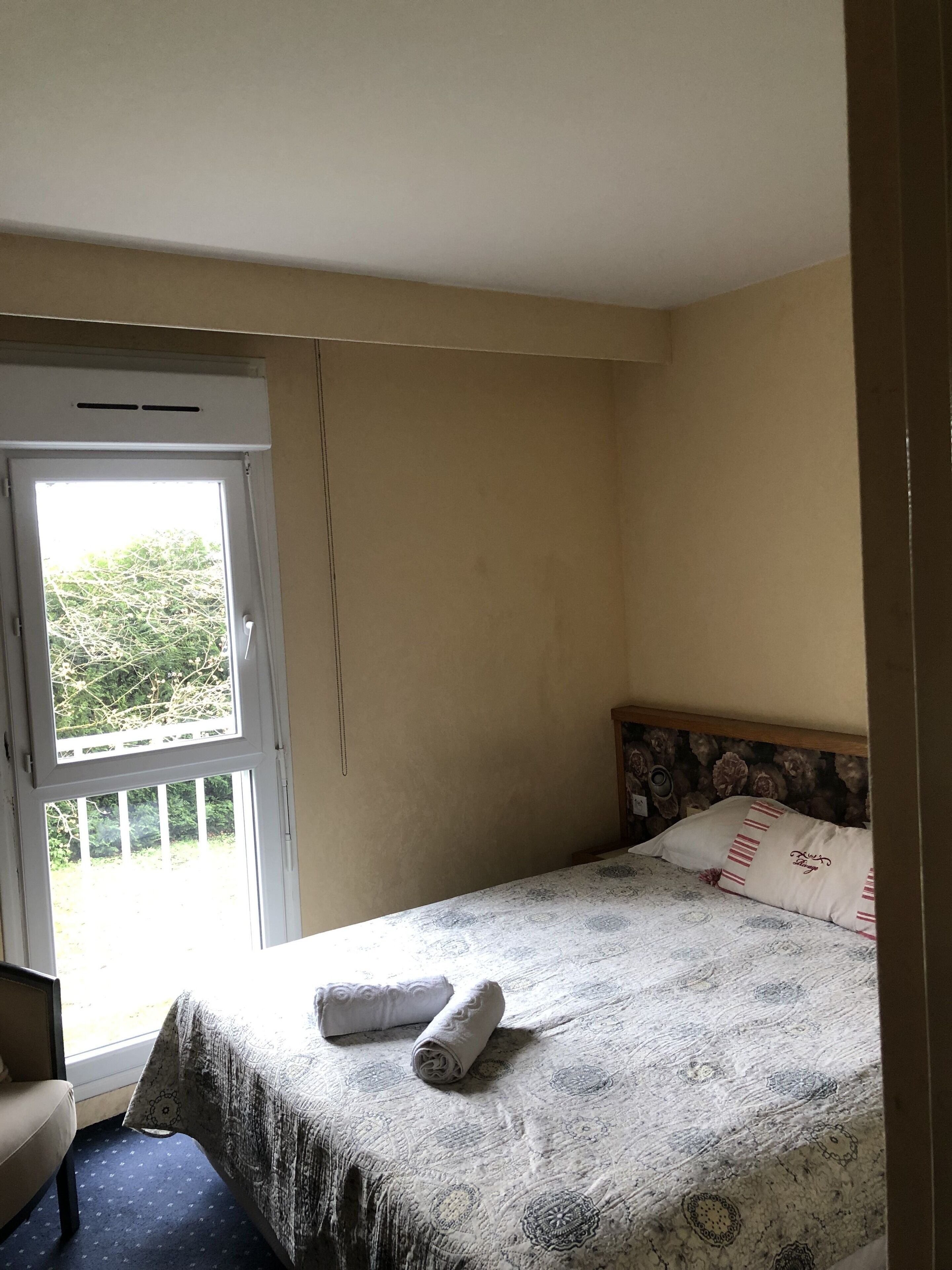 Ein Schlafzimmer mit einem Bett, einem Sessel und einem Fenster.