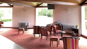 A covered outdoor seating area with wooden beams, a red carpet, and striped chairs. - Hotel Le Drakkar (Pont-Audemer)