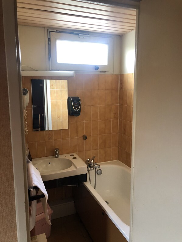 Un baño pequeño con dos lavamanos, un espejo, un perchero para toallas, un ventilador y una ventana.