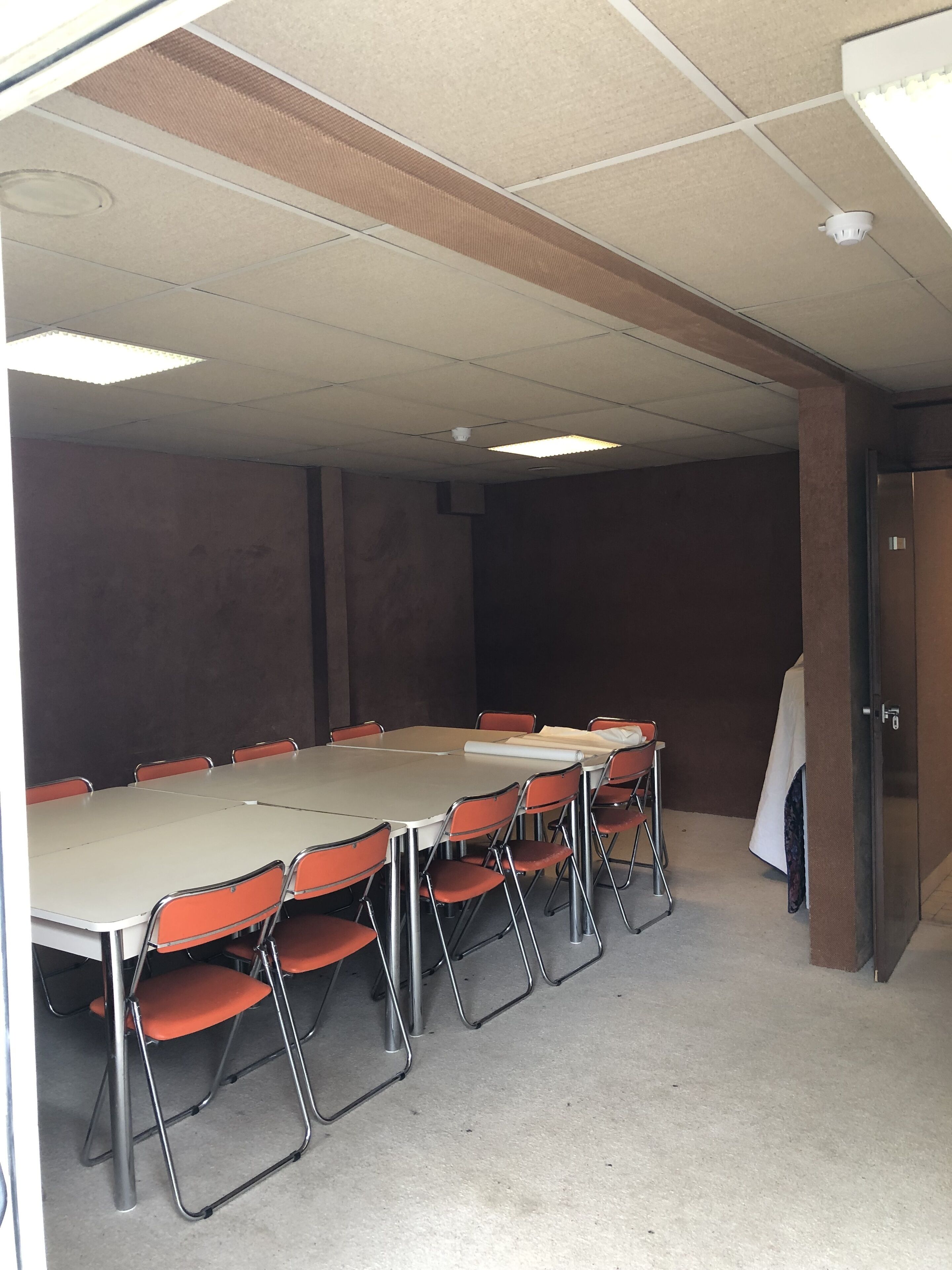 A conference room with a long table, orange chairs, and a whiteboard.