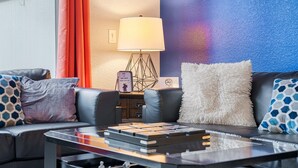 A modern living room with a sofa, a coffee table with books, a lamp, and a wall with a geometric pattern. - StarWars Theme + Free Waterpark | 10 min to Disney (Kissimmee)