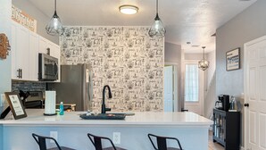 A modern kitchen with a central island, bar stools, and a backsplash with a nautical theme. - StarWars Theme + Free Waterpark | 10 min to Disney (Kissimmee)