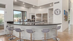 Una cocina moderna con una isla central, electrodomésticos de acero inoxidable y taburetes de bar.
