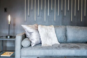 Un divano grigio con una soffice coperta e una lampada con una lampadina su un tavolino.