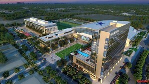 Een modern hotelcomplex bestaande uit meerdere gebouwen, met een zwembad op het dak en aangelegde tuinen.