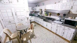 A kitchen with white cabinets, a gas stove, a microwave, and a small dining table with chairs. - 8MG-1 MANSION EN CARTAGENA CERCA AL MAR (Cartagena)
