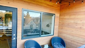 A wooden exterior with two large windows, a door, and two wicker chairs with cushions. - New Condo Walkable to Downtown Bozeman (Bozeman)