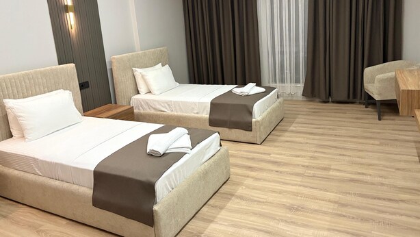 Une chambre d’hôtel avec deux lits, un plancher en bois, un bureau et une chaise.