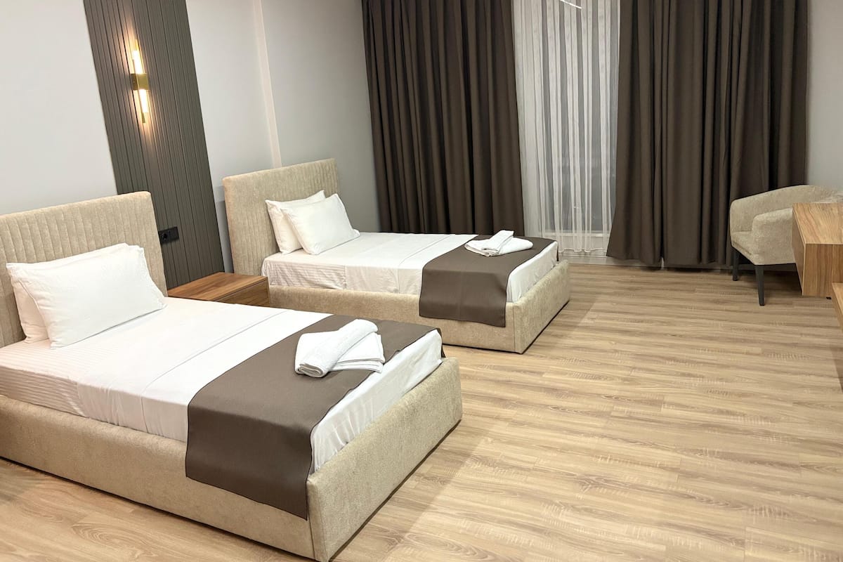 Une chambre d’hôtel avec deux lits, un plancher en bois, un bureau et une chaise.