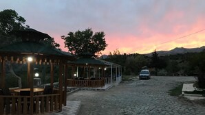 Un espace extérieur aménagé avec un kiosque, des tables et des chaises, un chemin pavé et une voiture garée.