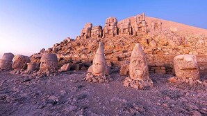 Un paysage désertique parsemé d’anciennes formations rocheuses et dominé par une grande structure pyramidale.