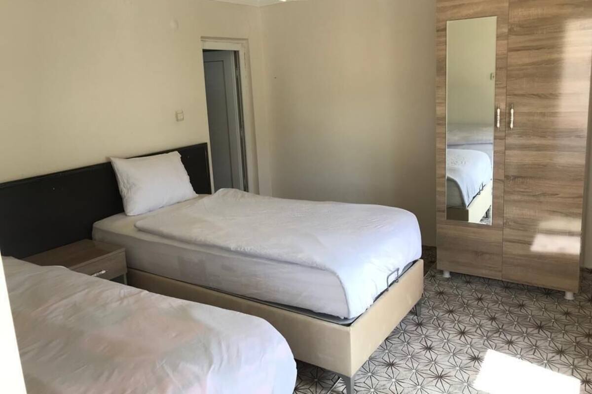 Une chambre avec deux lits, une armoire et un miroir.